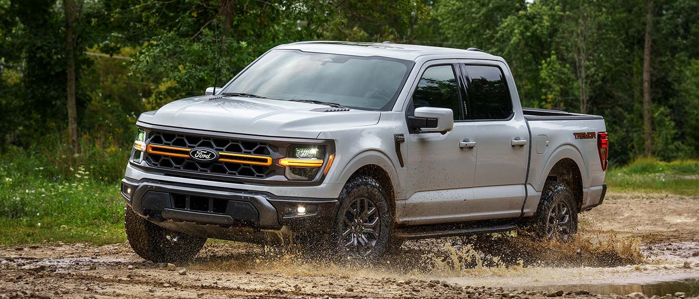 2025 Ford F-150® pickup driving through mud.